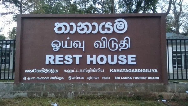 Signboard with text in multiple languages including Sinhala, Tamil, and English that reads 'Rest House' and is attributed to the Sri Lanka Tourist Board.
