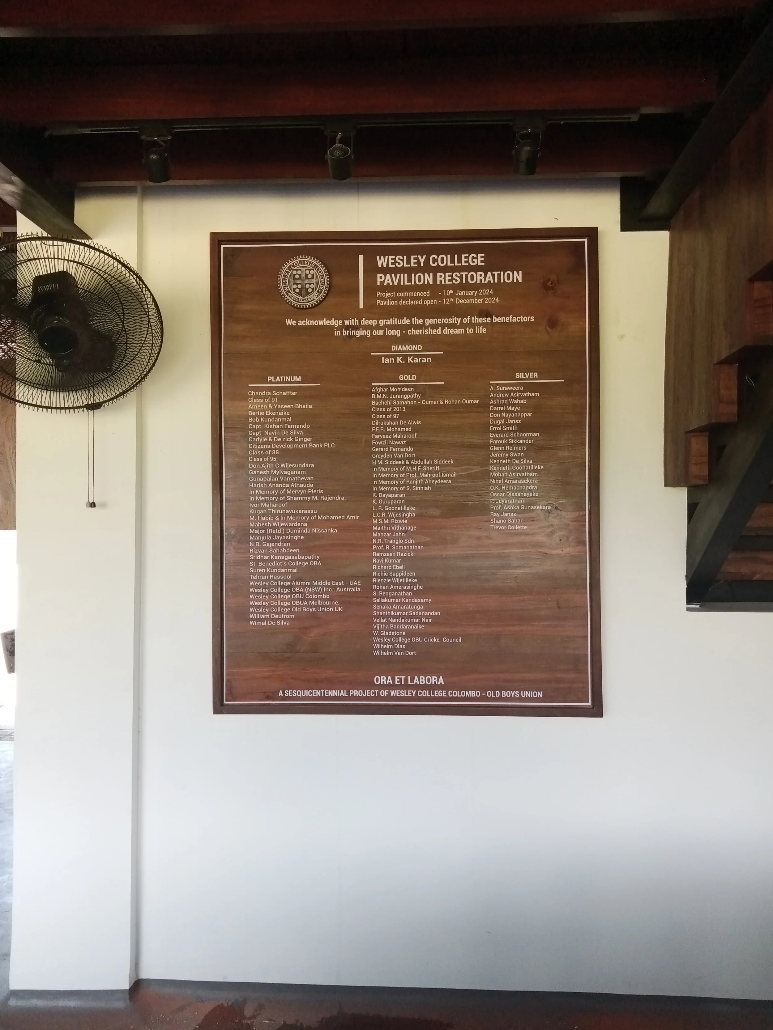 Wooden plaque with text acknowledging the Wesley College Pavilion Restoration project, displaying donors' names categorized as Diamond, Platinum, Gold, and Silver, with a Wesley College crest logo at the top.