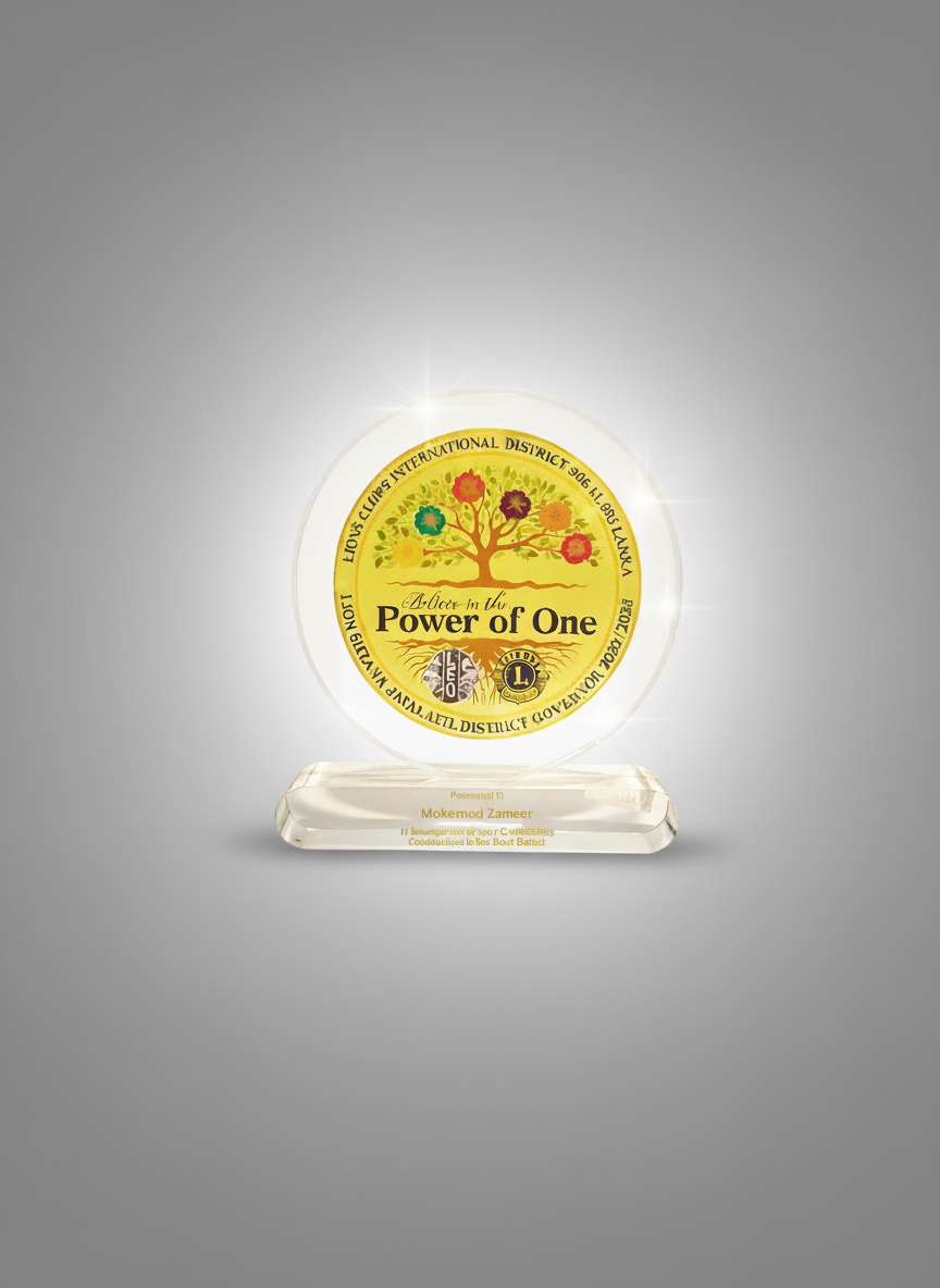 A commemorative glass plaque with a glowing illumination, featuring a logo with a tree and the text "A Leader in the Power of One." The plaque also has a base with the name Nick Zang in gold lettering.