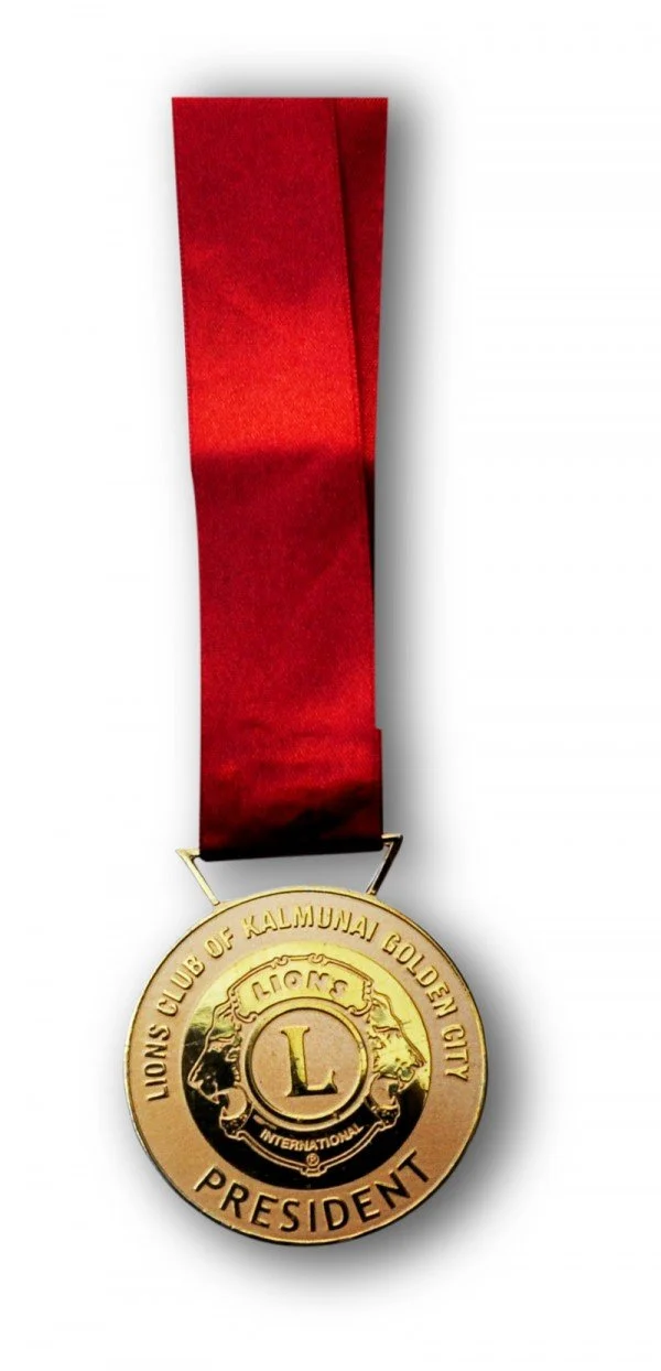 Gold medal with a red ribbon, inscribed with 'Lions Club of Kallumai Golden City' and 'President', featuring two lion heads and the letter 'L' in the center.