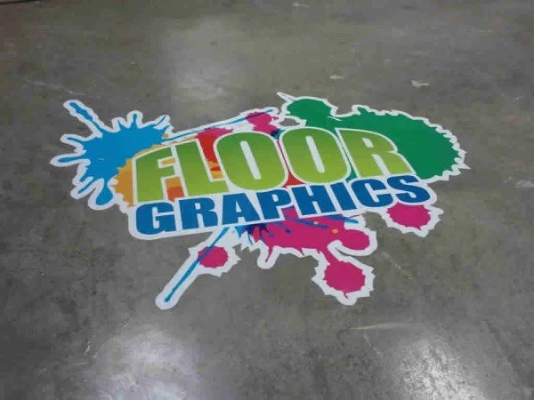 Colorful floor graphic with the words 'FLOOR GRAPHICS' in green, orange, blue, and pink, surrounded by paint splatters.