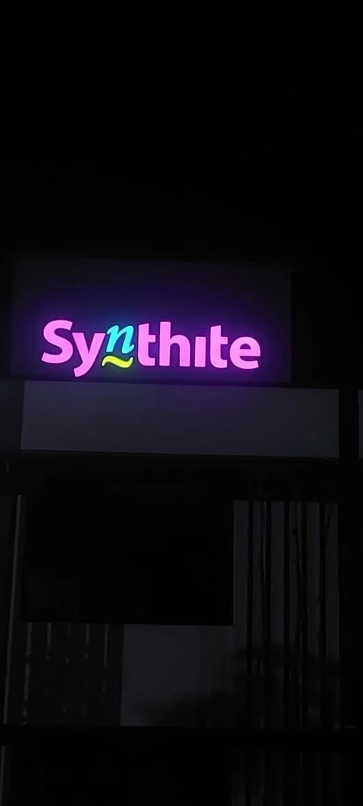Neon sign displaying the word 'Synthite' with colorful text on a dark background.