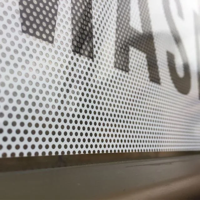 Close-up of a printed sign or banner with black text on a white perforated surface.