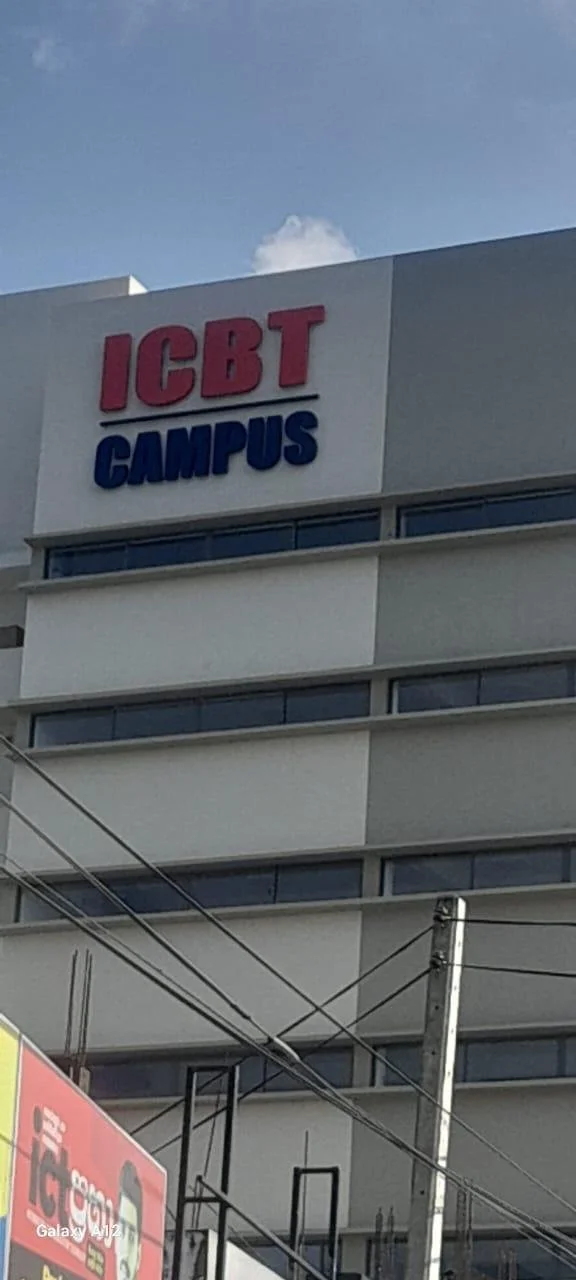 Sign on a building that reads "ICBT CAMPUS" with "ICBT" in red and "CAMPUS" in blue, located on a white multi-story building under a blue sky.