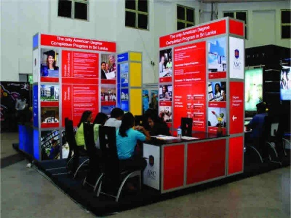 Students studying at an American degree completion program information booth in Sri Lanka with red and blue display panels.