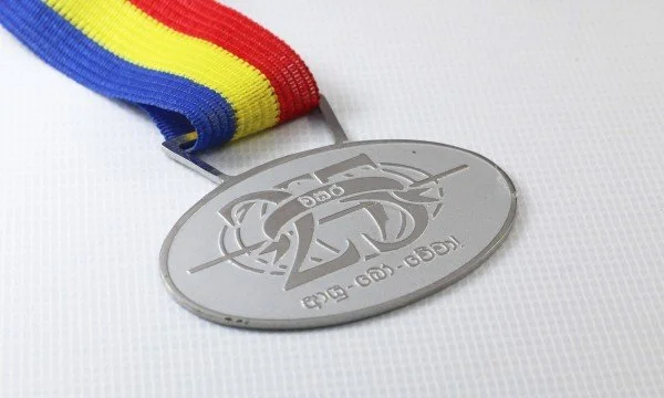 A silver medal with a rainbow-colored ribbon featuring blue, yellow, and red stripes, attached to the medal.