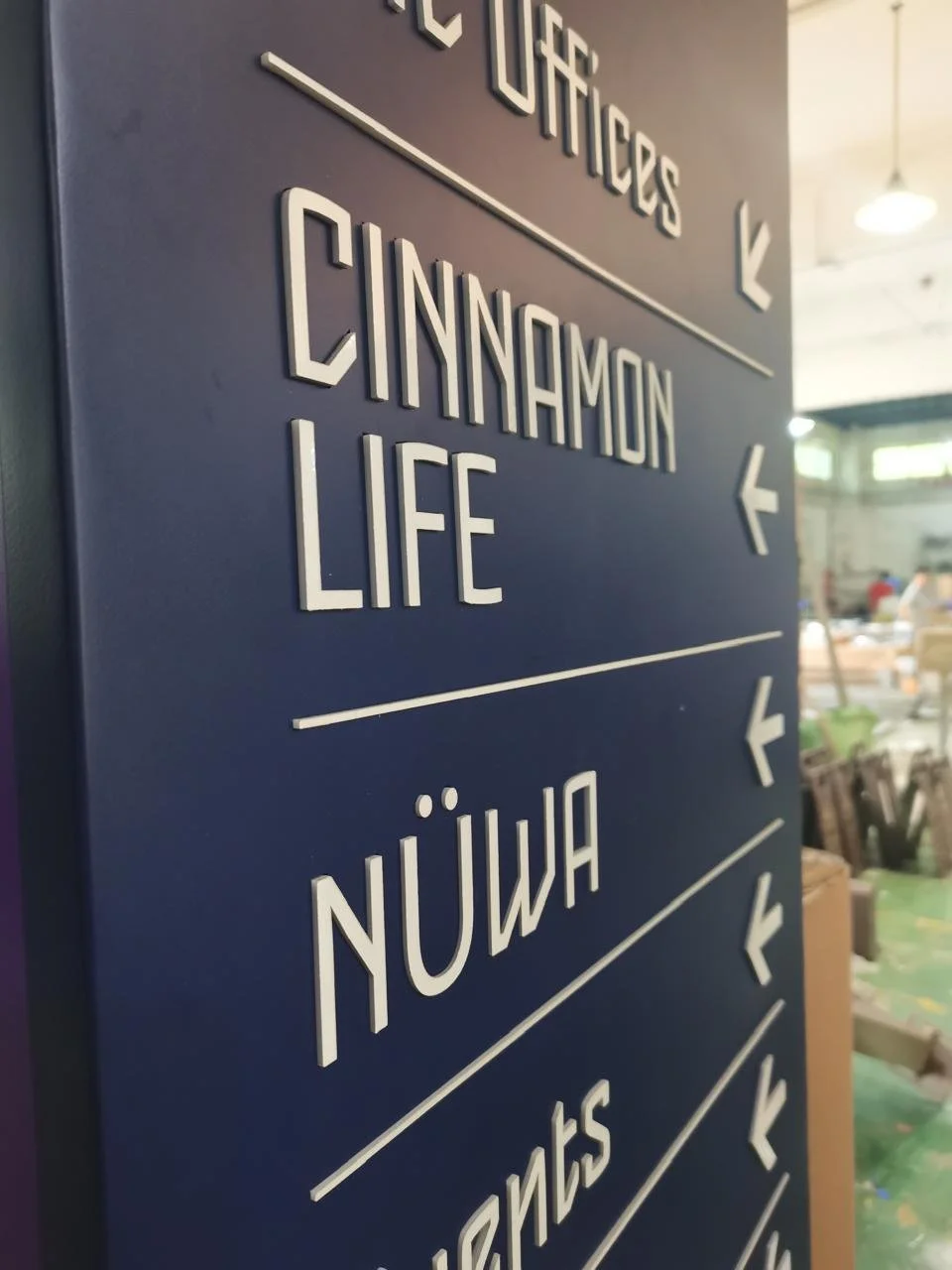 A blue directional sign with white text and arrows pointing left and right, indicating directions to various local attractions and neighborhoods.