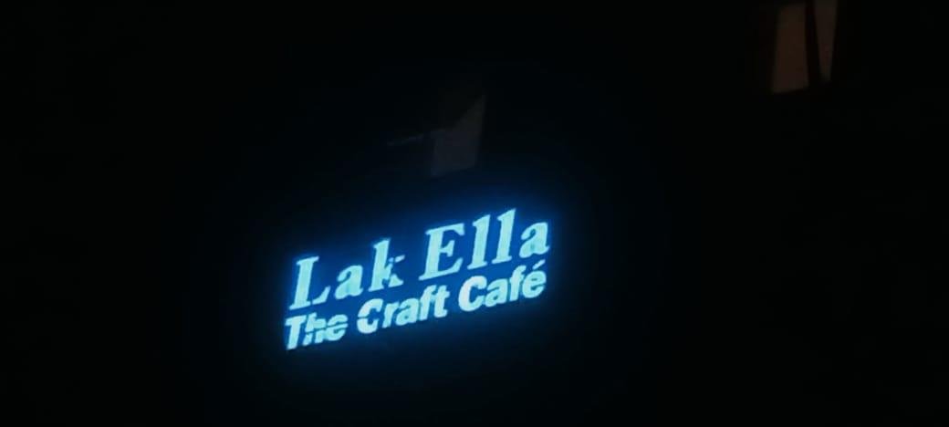 Illuminated sign for 'Lake Ella The Craft Café' at night.