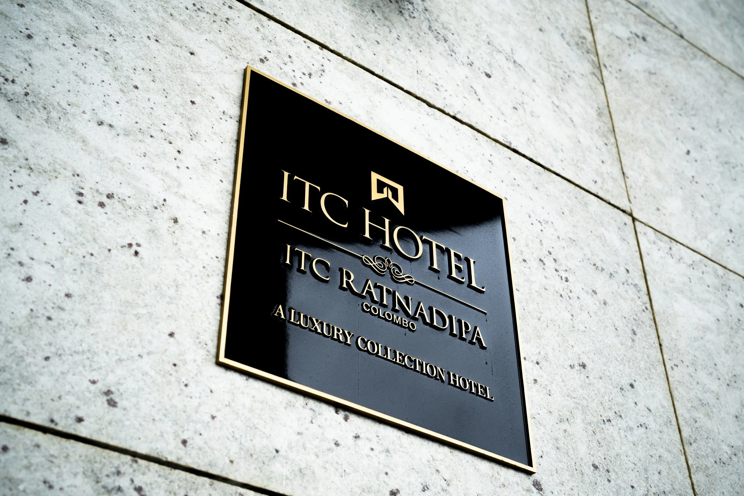Black sign on a beige wall displaying the name of a hotel, "ITC Hotel ITC Rajputana Colombo Luxury Collection Hotel".