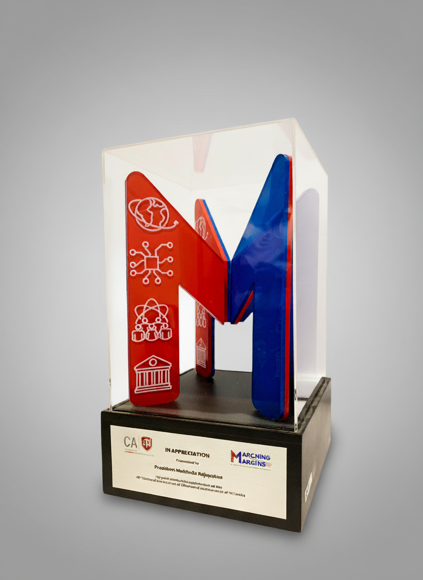 A decorative sculpture of the letter M, with red and blue colors, displayed inside a clear case. The base has a plaque with appreciation text.