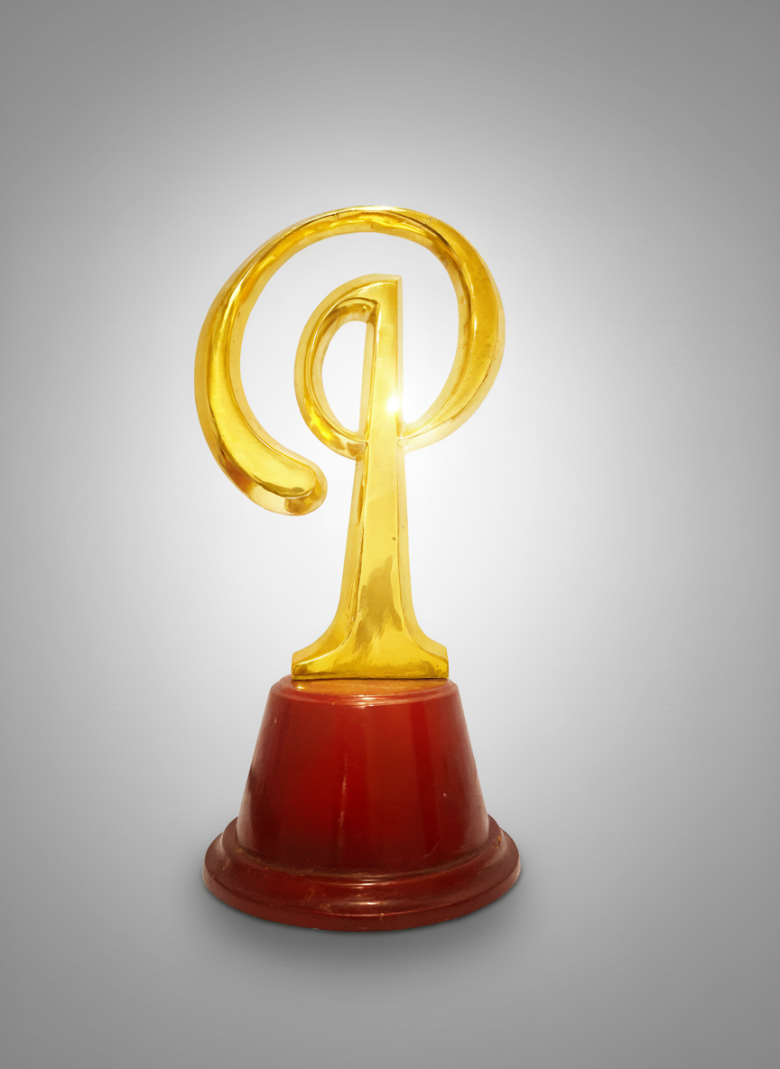 Golden trophy shaped like the at symbol (@) on a red base.