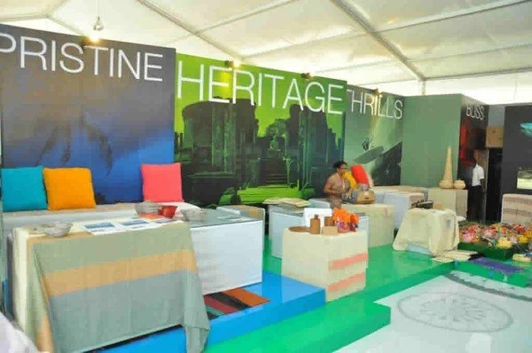 Exhibition booth with banners displaying 'PRISTINE HERITAGE HILLS' and arranged tables with various items for display or sale.