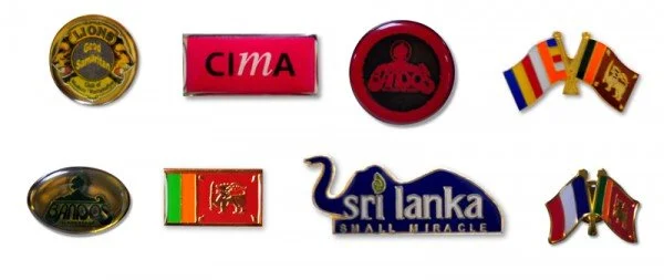 Collection of eight pins featuring various logos and flags, including Sri Lankan cricket team, CIMA, and national flags of France, Sri Lanka, and Portugal.
