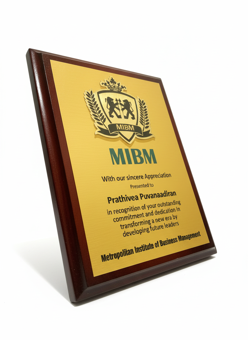 A recognition plaque with a gold and brown design, featuring the MIBM logo at the top, and an inscription recognizing Prathivea Puvanaadiran for outstanding commitment and dedication, presented by the Metropolitan Institute of Business Management.
