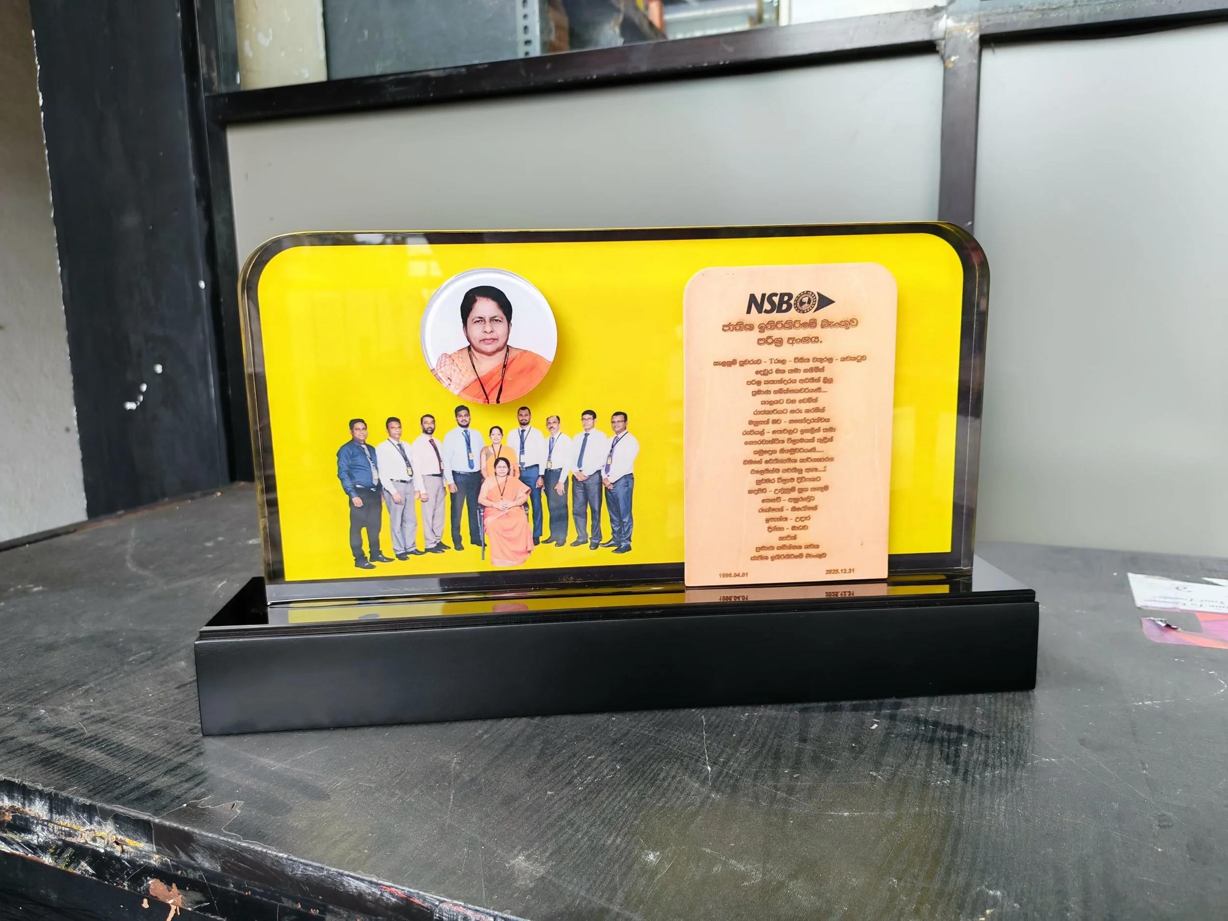 Yellow poster with a photo of a woman wearing traditional attire, along with a group of people dressed in formal clothing and a paragraph of text written in Sinhalese. The poster appears to be related to a political organization.