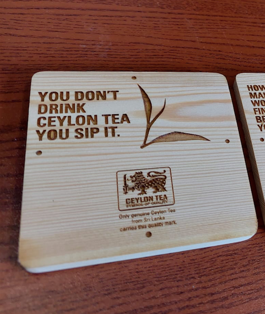 Wooden sign with a quote about drinking Ceylon tea, a leaf illustration, and a logo that says Ceylon Tea with a lion emblem.