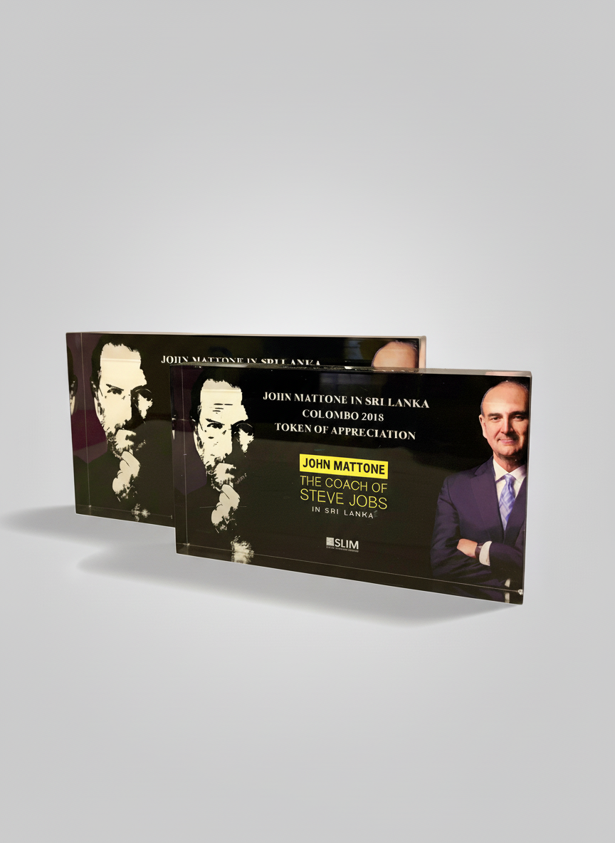 Two black plaques promoting John Mattone, titled 'Join Mattone in Sri Lanka Colombo 2018 Token of Appreciation'. The plaque features a photo of John Mattone in a suit, crossed arms, smiling, with the text 'The Coach of Steve Jobs' below, and a styliz