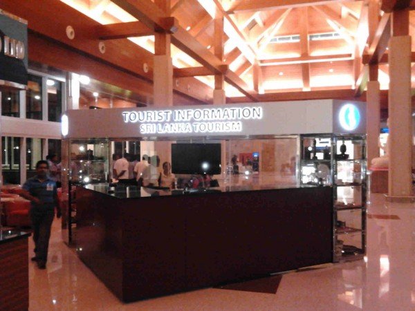 Tourist information desk for Sri Lanka tourism inside an airport or shopping mall with a black counter and a sign overhead.