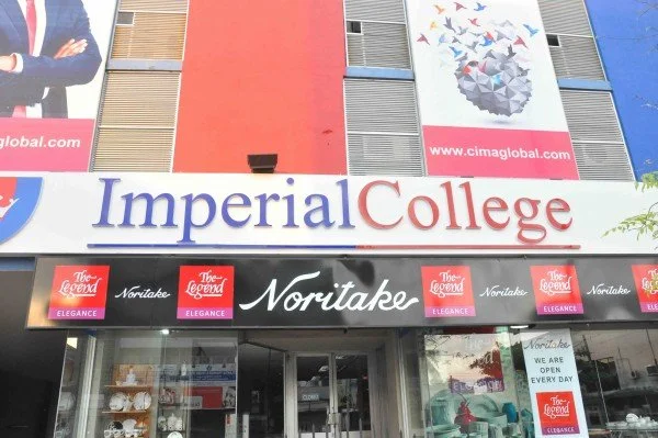 Facade of Imperial College educational building with signs for 'Noritake' and 'The Legend Elegance' on the storefront.