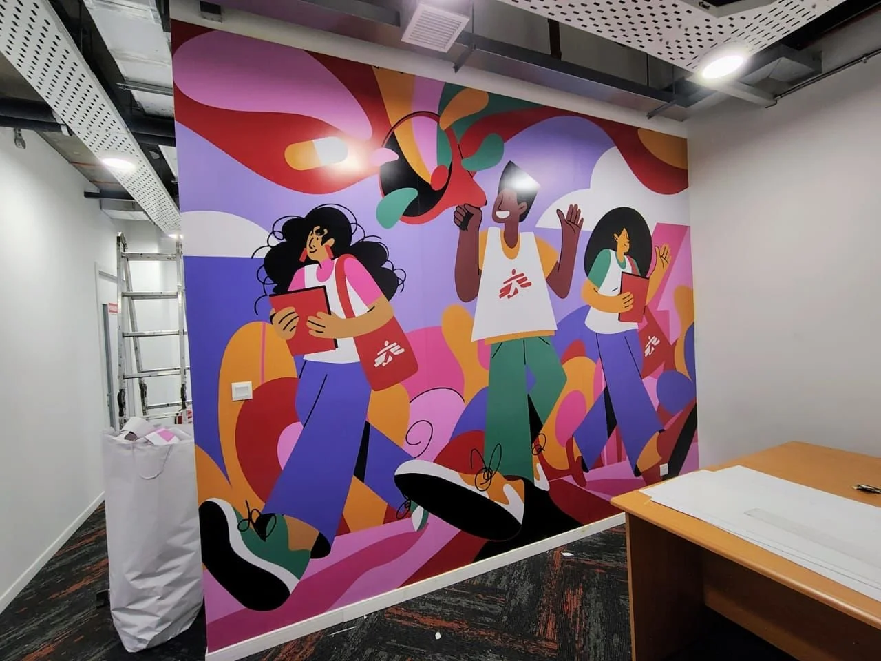 Colorful mural of three young people walking with books and backpacks, surrounded by abstract shapes and vibrant colors.