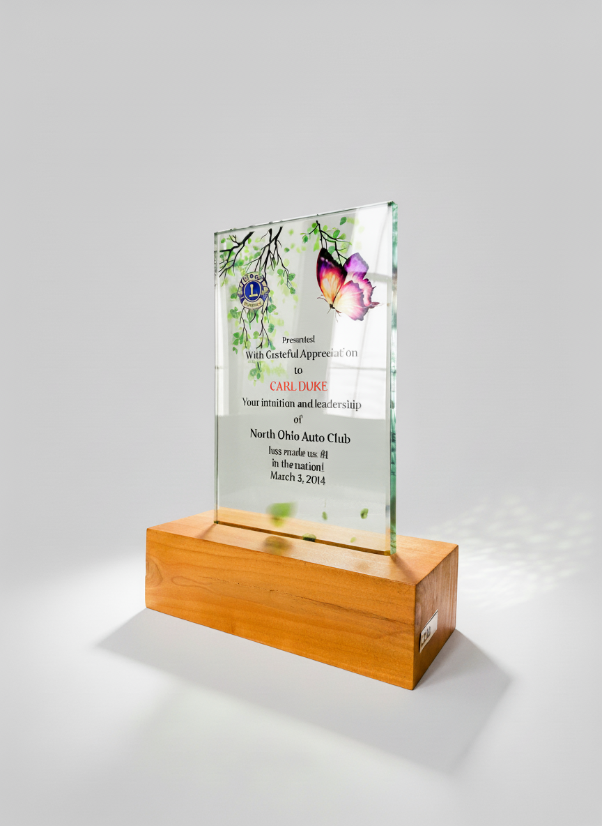 A glass award with a wooden base, featuring a butterfly and green leaf design, inscribed with a thank you message to Carl Duke from North Ohio Auto Club, dated March 3, 2014.