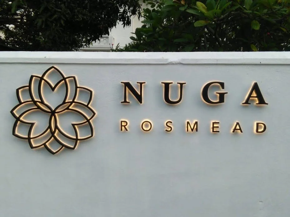 Sign with the text "Nuga Rosmead" and a floral logo on a white background.