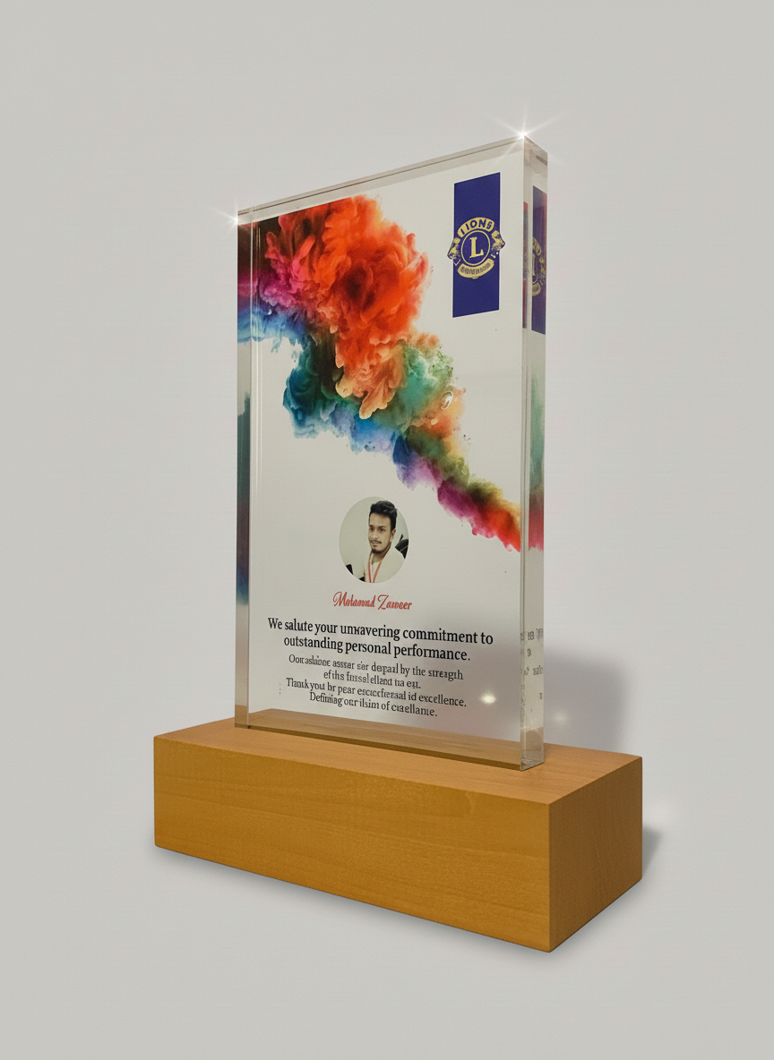 A glass award with a colorful cloud design at the top, a photograph of a man with dark hair and a light beard, and text including a name, a message of congratulations, and a Lions Club logo on the top right corner, all mounted on a wooden base.