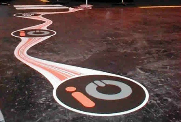 A floor with a design that looks like a winding record player tonearm and stylus, featuring the words 'I' and 'O' within circular shapes.