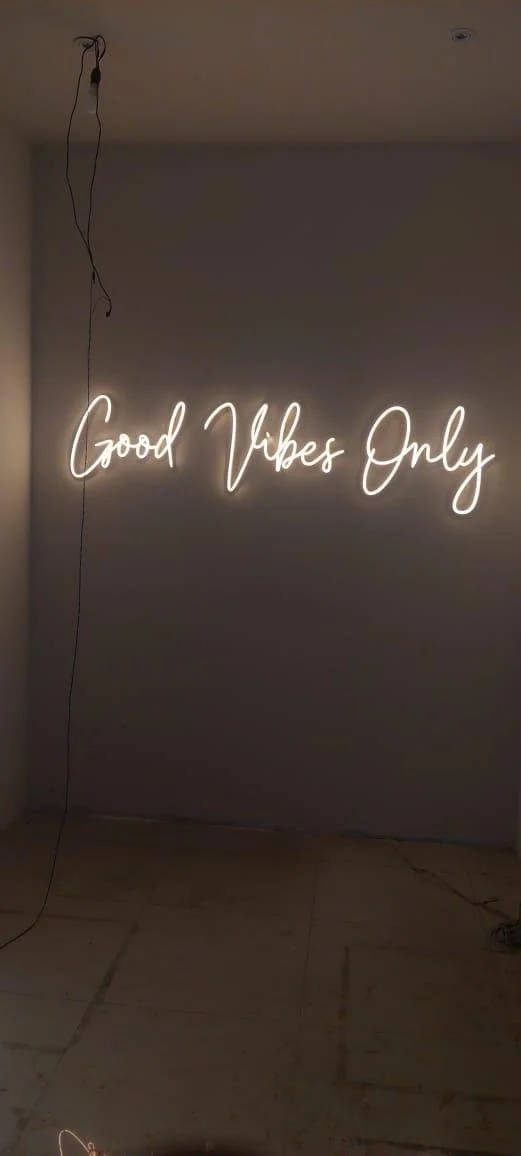 A neon sign on a wall that reads "Good Vibes Only" in cursive script.