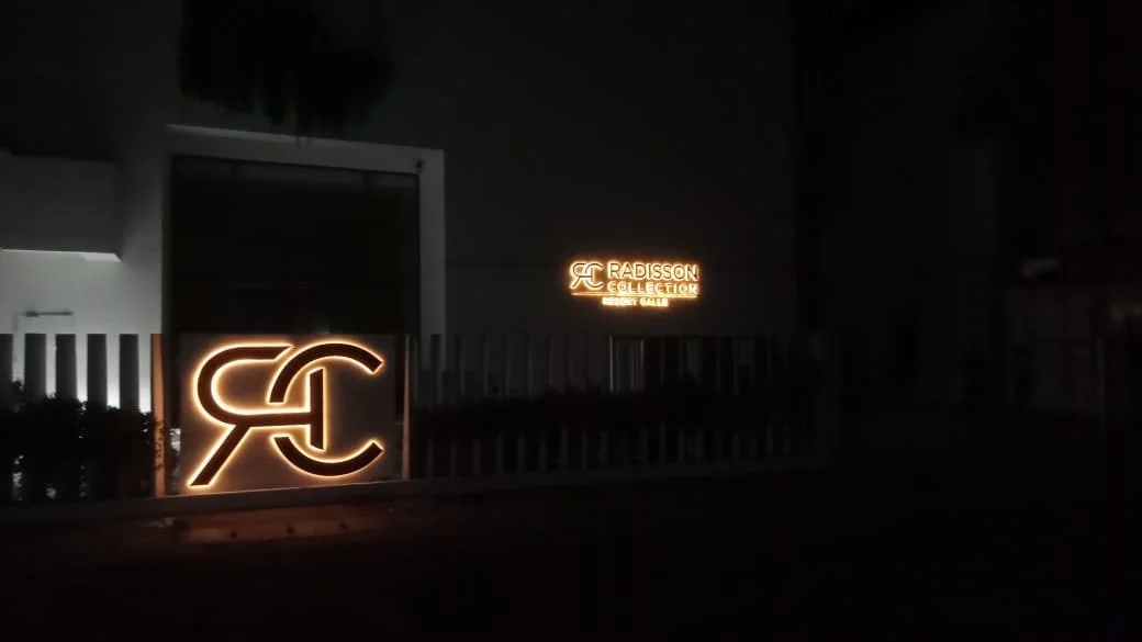 Night-time scene of illuminated signage for Radisson Collection hotel, featuring a logo and text reading 'Radisson Collection' and 'Sleep Well'.