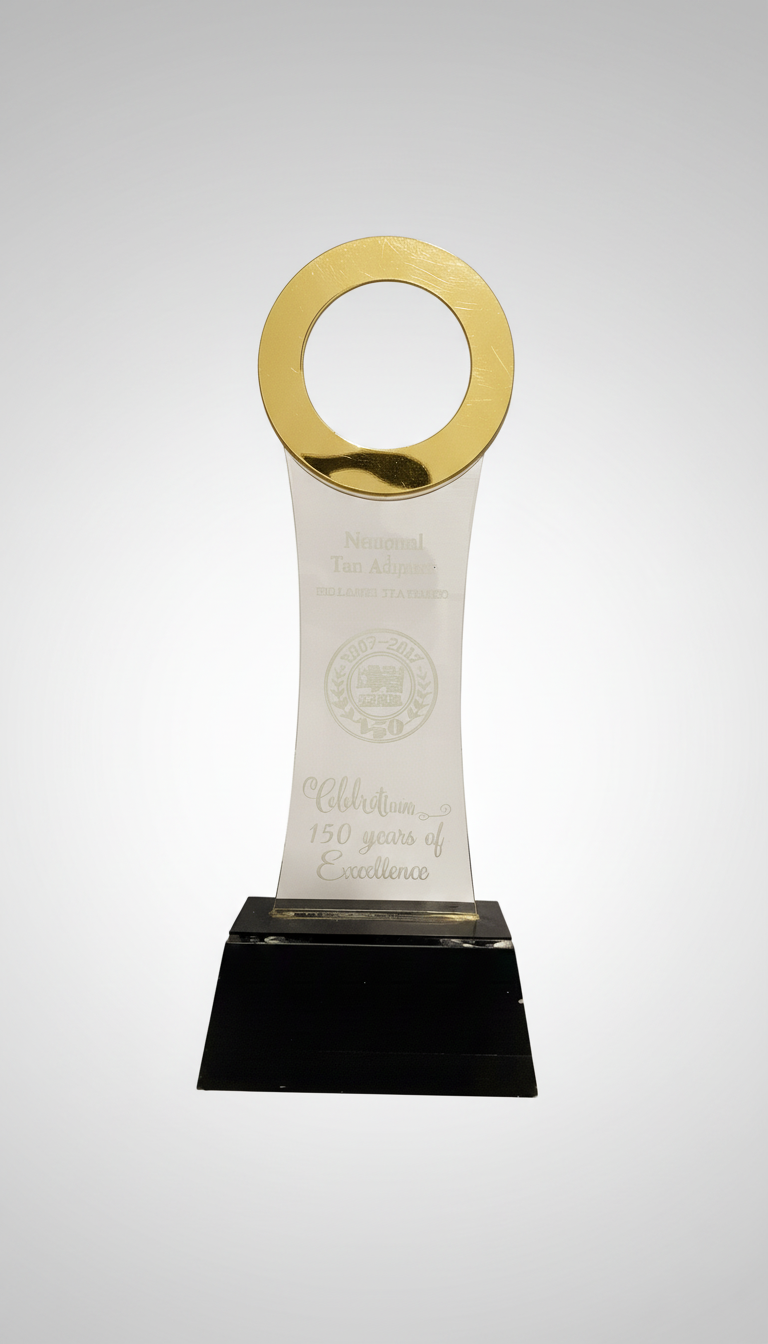 A clear award trophy with a gold circular top, inscribed with 'Celebrating 150 years of Excellence.'