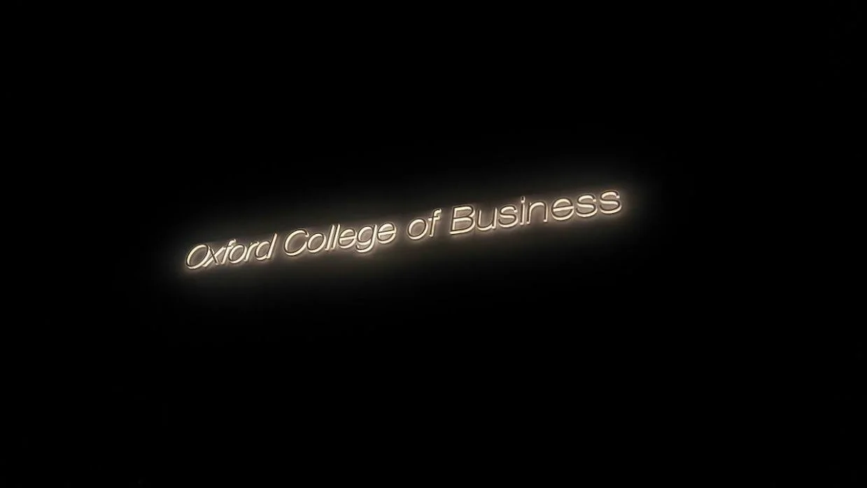 Neon sign displaying 'Oxford College of Business' against a black background.