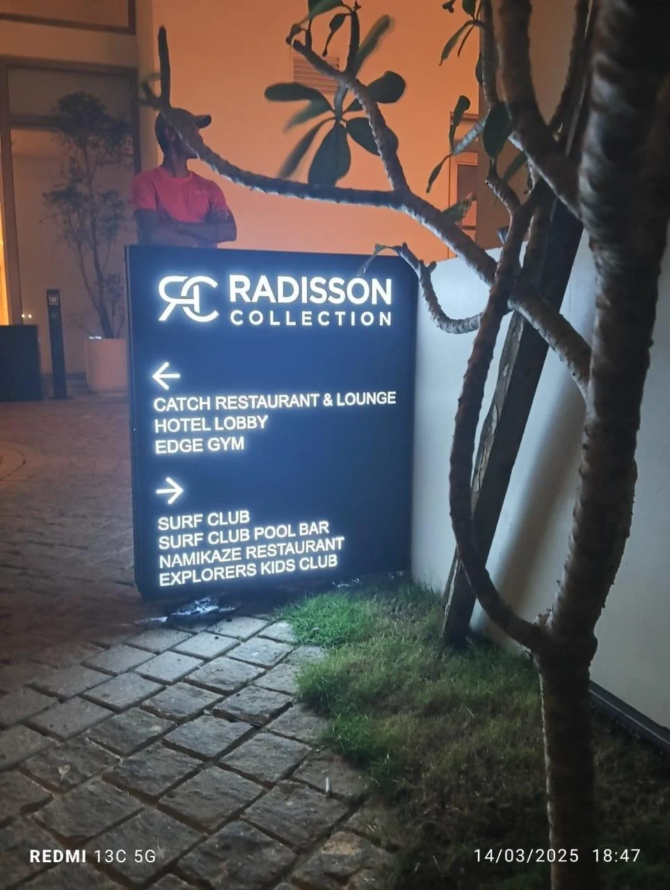 Illuminated directory sign for Radisson Collection hotel with arrows pointing left and right, listing amenities and attractions nearby.