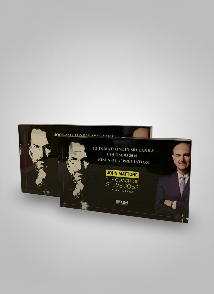 Two black plaques with a photo of Steve Jobs on the right and a man in a suit on the left, with text about a token of appreciation for John Mattone in Sri Lanka, Colombo 2018.