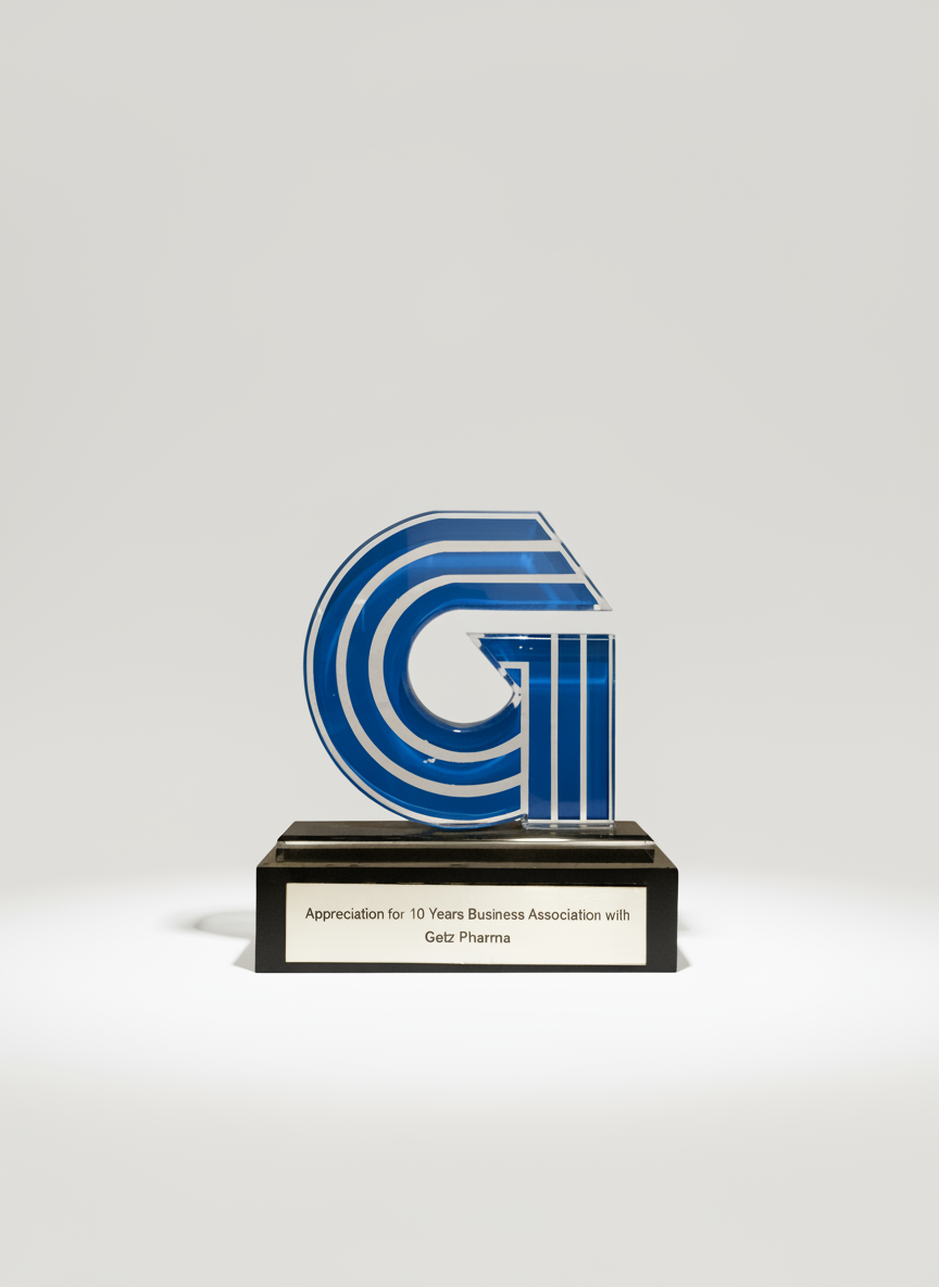 Glass trophy with blue and white striped logo, inscribed with 'Appreciation for 10 Years Business Association with Getz Pharna' on black base.