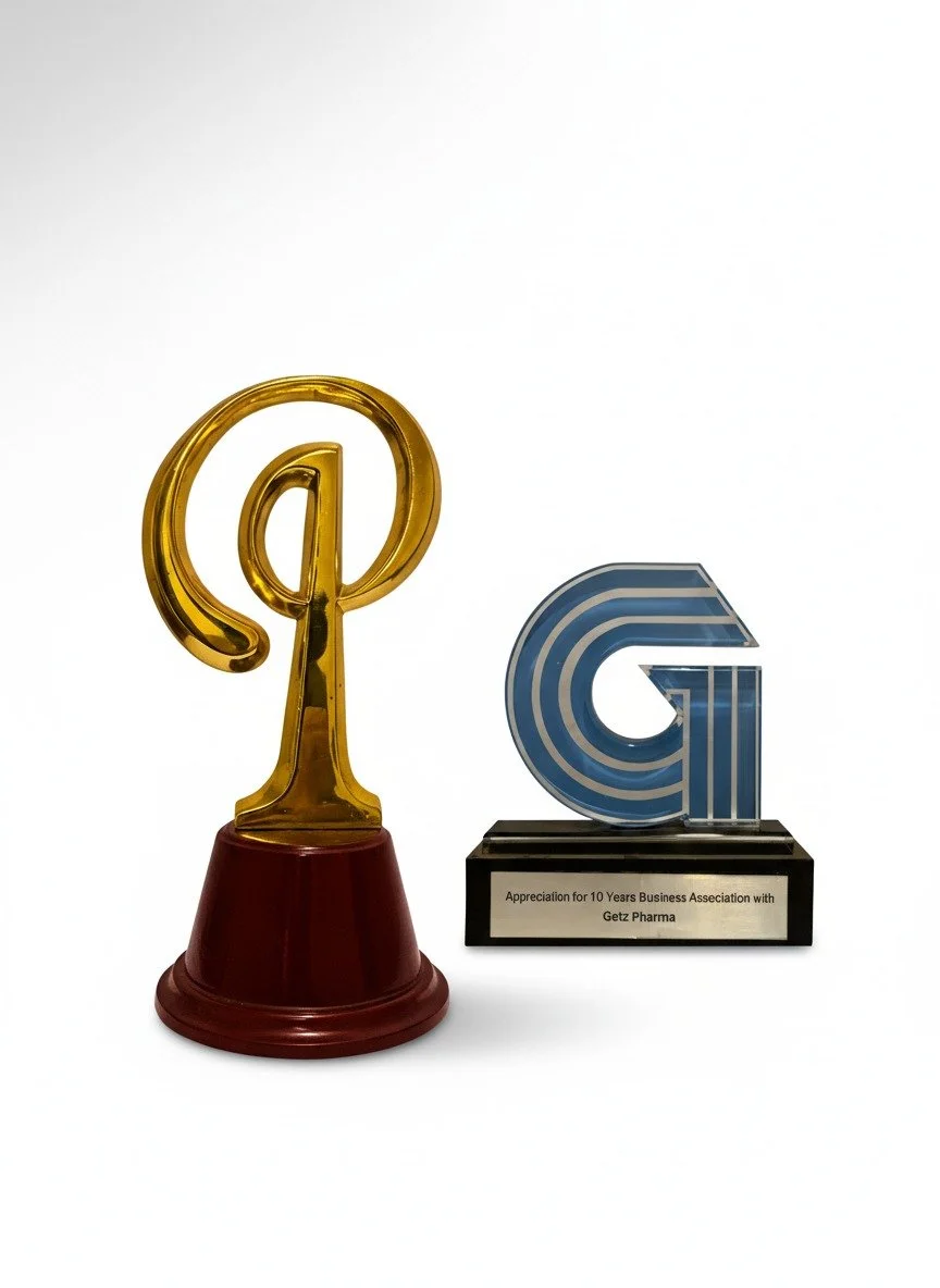 Two trophies, one gold with a red base and one blue with a black base, celebrating a 10-year business alliance with Getz Pharma