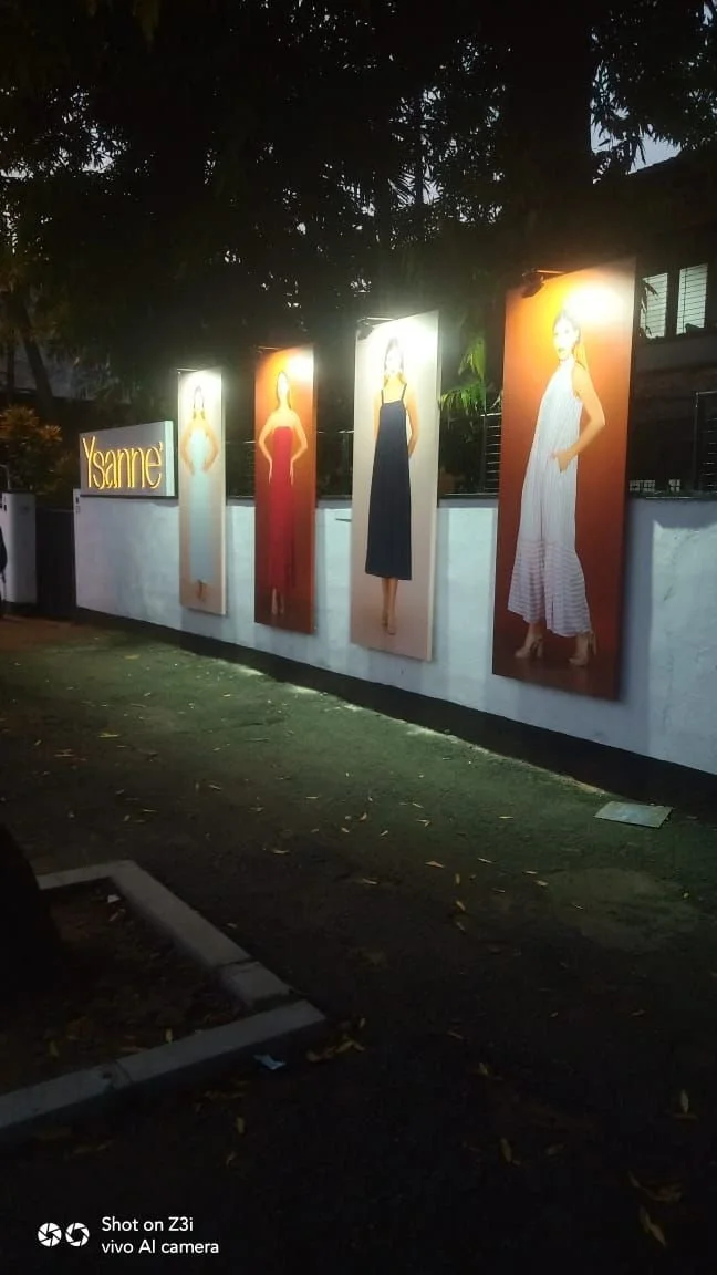 Outdoor display of four mannequins wearing dresses, with a sign reading 'Ysaine' on the wall.