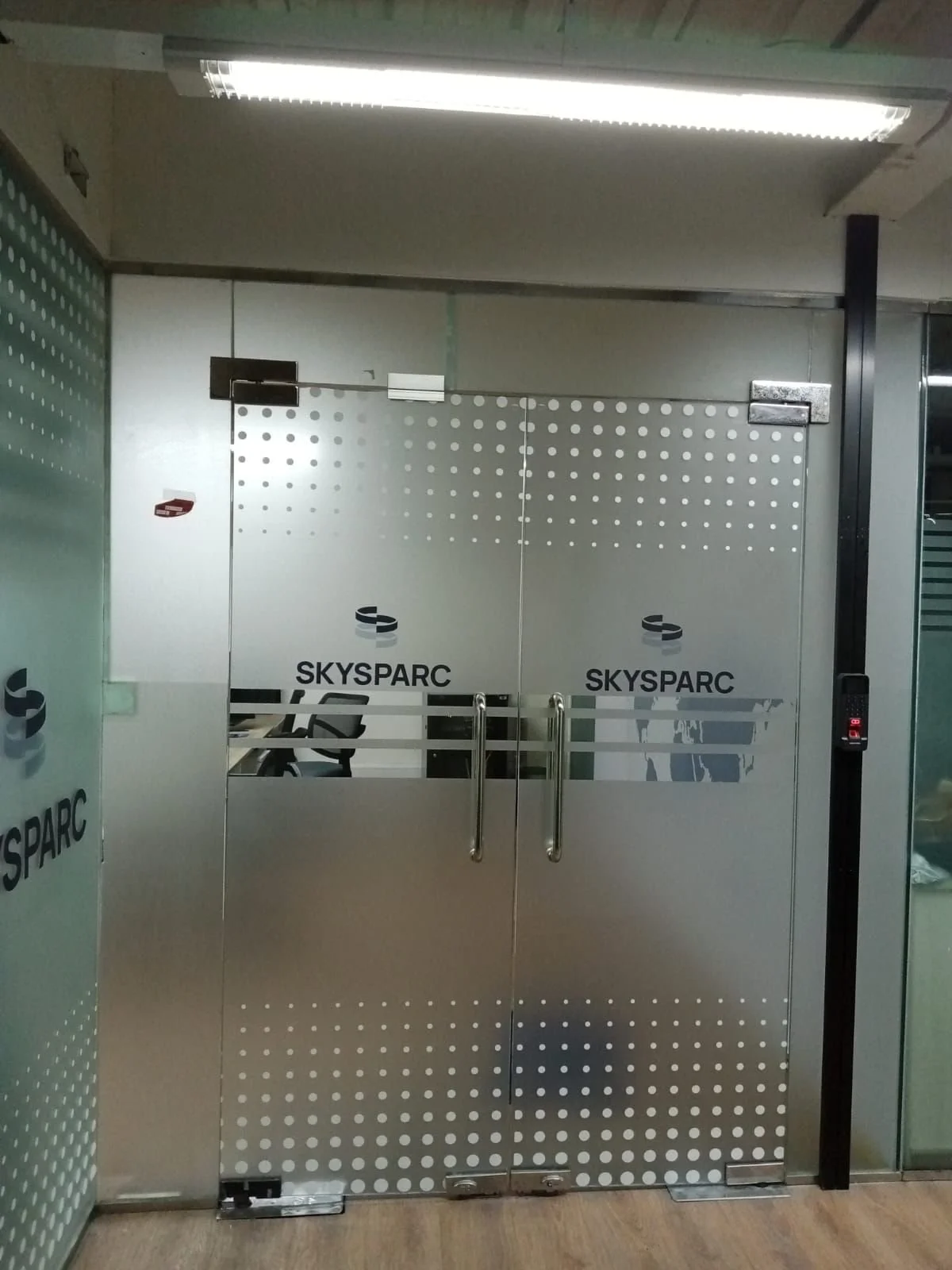 Glass doors with the logo for SKYSARC and a chair visible inside, in a modern office setting.