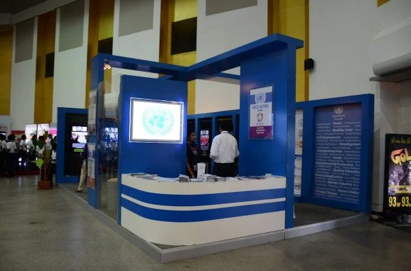 A United Nations booth at an indoor event with display screens and informational posters.