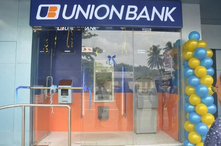 Front of a UnionBank branch decorated with blue and yellow balloons, with a glass door entrance and an Automated Teller Machine (ATM) inside.