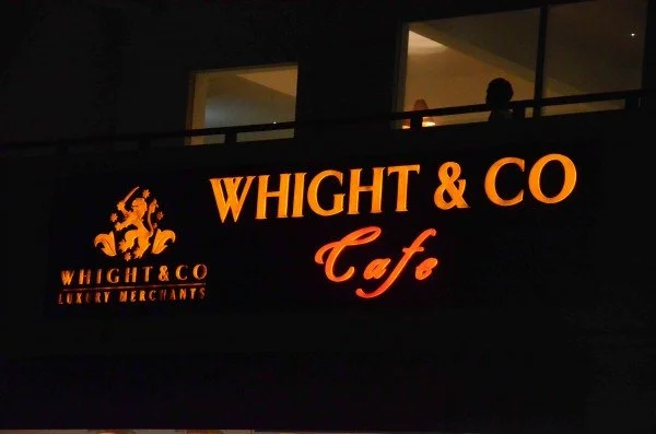 Sign for Whight & Co Cafe with logo and text in orange on a black background.