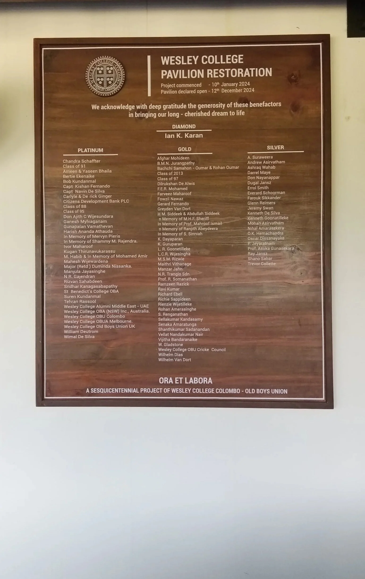 A wooden plaque listing donors and project details for the Wesley College Pavilion Restoration, including project start date, December 2024, and acknowledgment of benefactors categorized as diamond, platinum, gold, and silver donors.