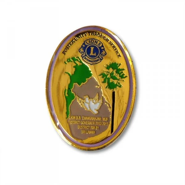 A Lions Clubs International badge with a gold and purple border, featuring the Lions logo at the top and a map of Sri Lanka with green and gray parts, along with symbols of a tree and a hand, and text indicating district and governor information.