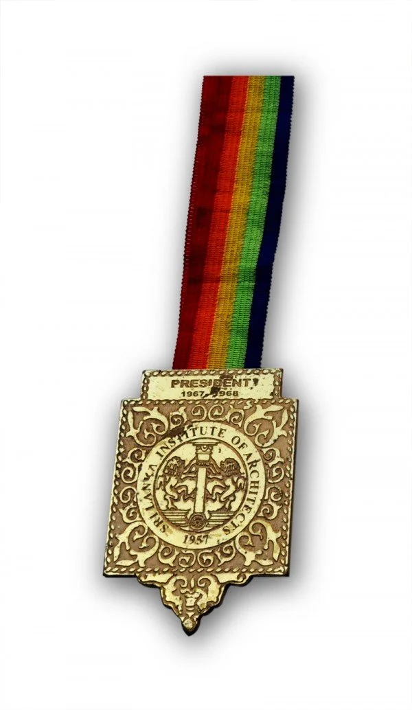 A medal with a colorful rainbow ribbon attached to a decorative plaque from the Sri Lankan Institute of Architects, awarded for Presidential Merit, 1951, with an additional small ribbon indicating the years 1967-1968.