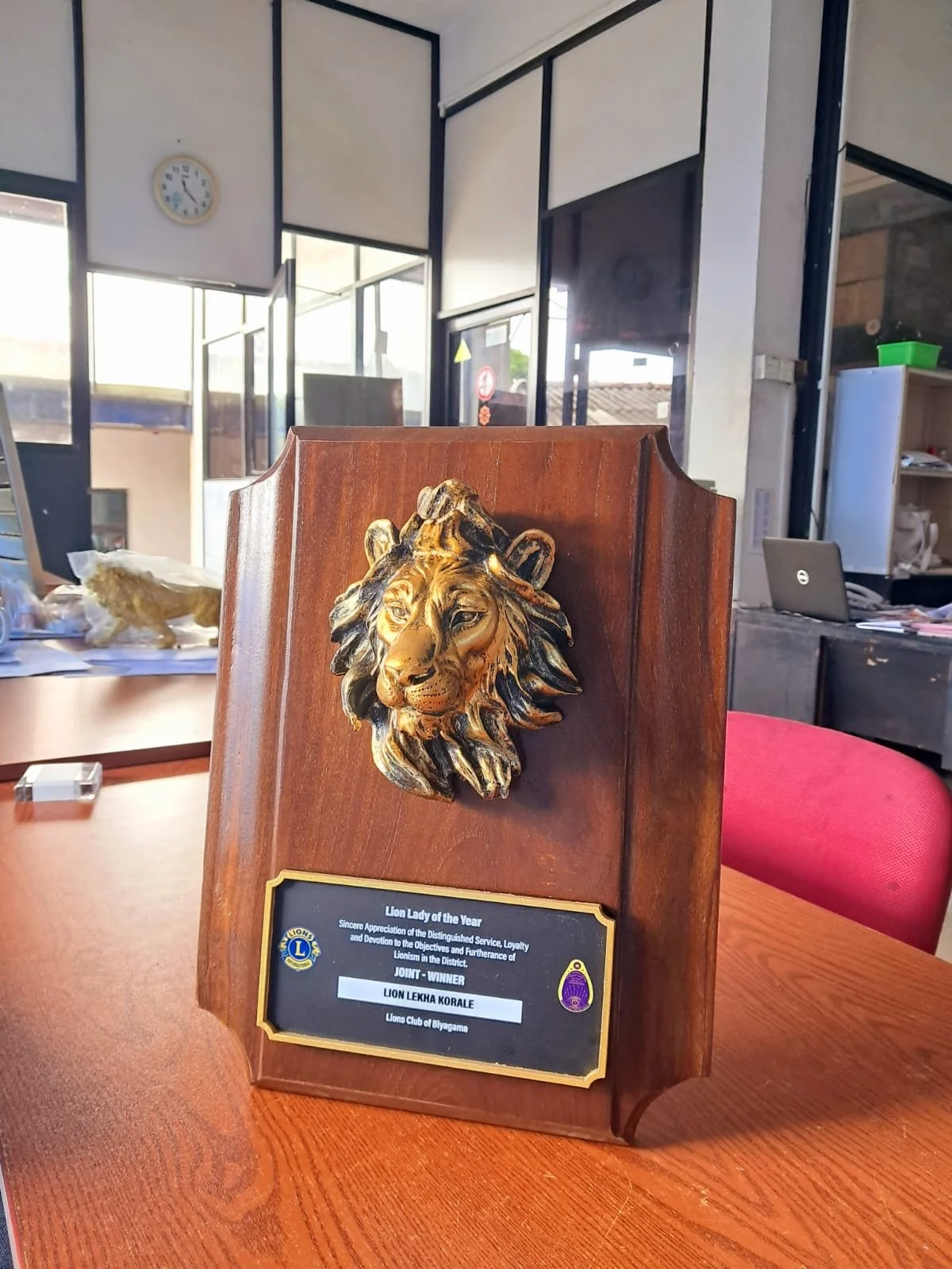 Wooden plaque with a gold-colored lion's head and a plaque that reads 'Lion Lady of the Year' awarded by Lions Club of Biyagama.