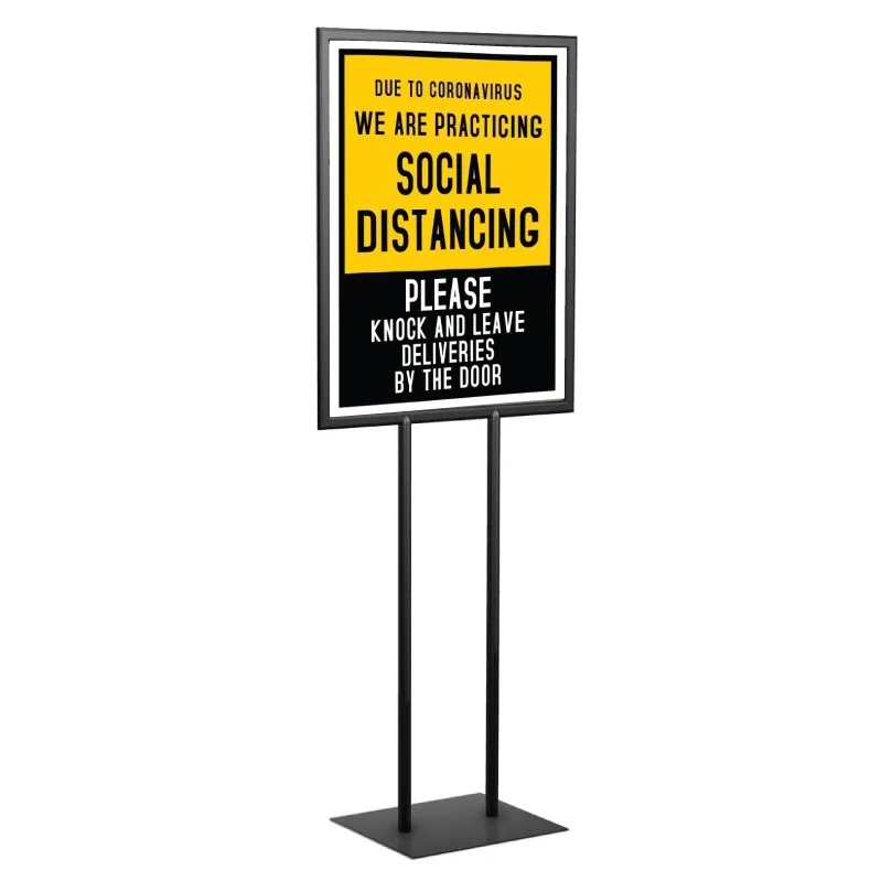 Signboard with yellow and black background indicating social distancing and encouraging people to knock and leave deliveries by the door due to coronavirus.