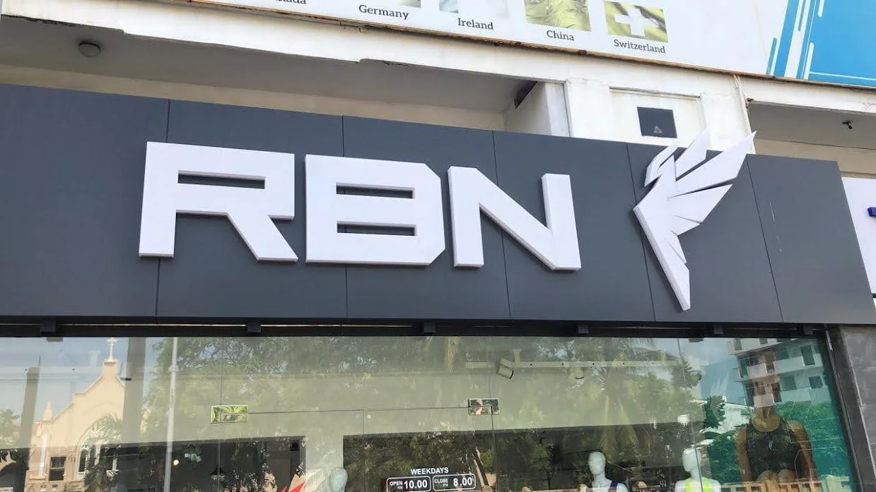 Store sign with the word 'REYN' in bold, stylized white letters and a white feather-like graphic to the right of the text.