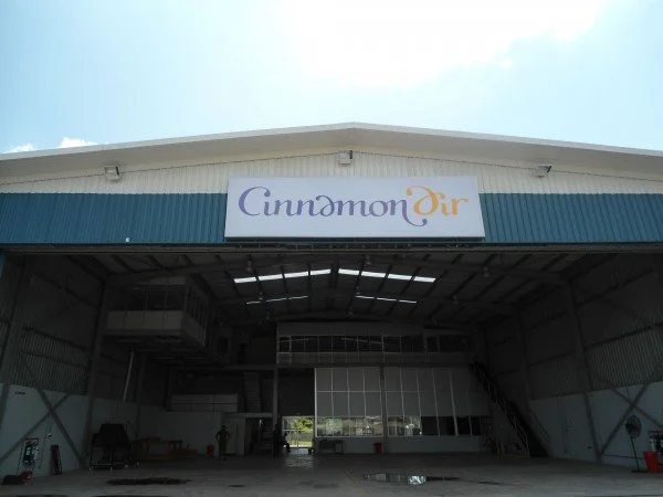 Exterior of a large aircraft storage hangar with a sign that reads "Cinnabon Air"