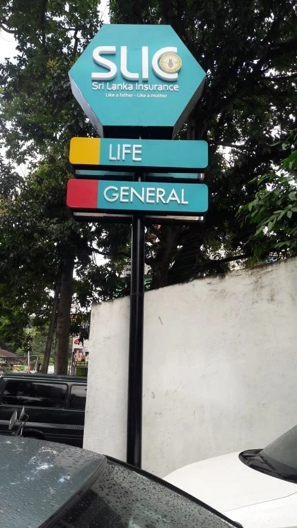 Signboard of Sri Lanka Insurance with the logo and the slogan "Like a father - Like a mother". It advertises life and general insurance services.