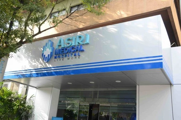 Exterior of Asiri Medical Hospital with blue logo and signage, trees in the foreground.